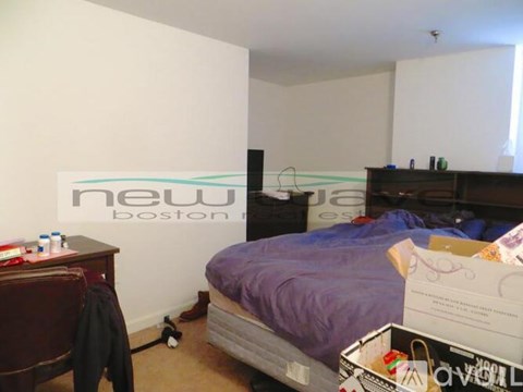 A room with a bed, a chair, and a box on the floor.