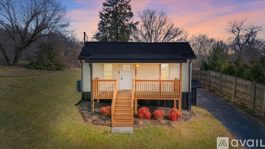 A small house with a porch and a fence in the background.