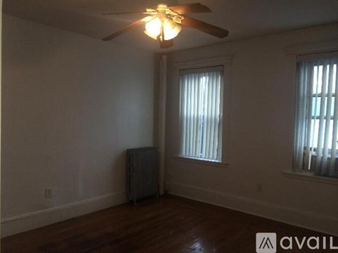 A room with a ceiling fan and two windows.