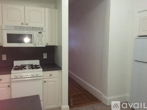 A kitchen with white cabinets and a black countertop.