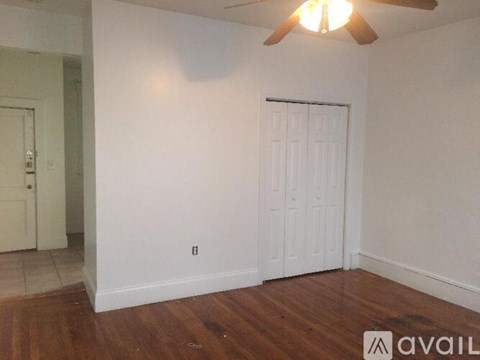 A room with a white door and a ceiling fan.