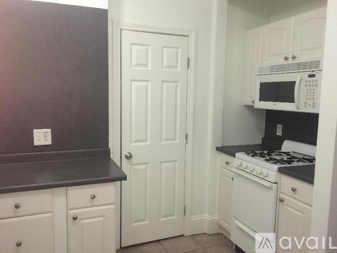 A kitchen with white cabinets and a black countertop.