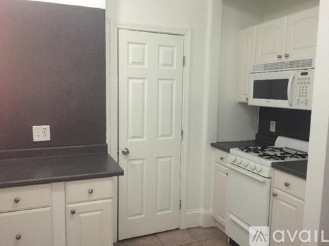 A kitchen with white cabinets and a black countertop.