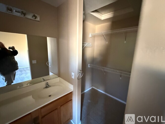 A bathroom with a sink, mirror, and a person taking a picture.
