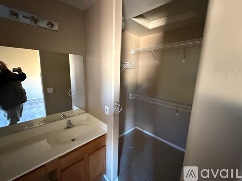 A bathroom with a sink, mirror, and a person taking a picture.