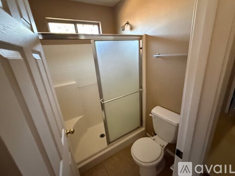 A small bathroom with a toilet, sink, and shower.