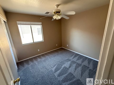 A room with a carpeted floor and a ceiling fan.