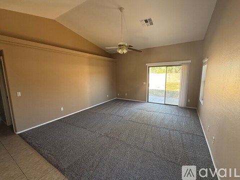 A spacious room with a ceiling fan and sliding glass doors leading to a patio.