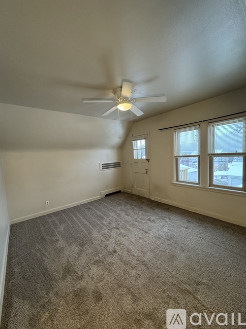 A room with a carpeted floor and a ceiling fan.