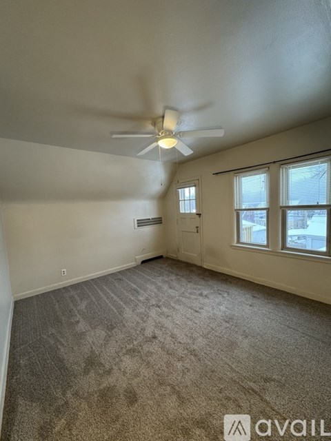 A room with a carpeted floor and a ceiling fan.