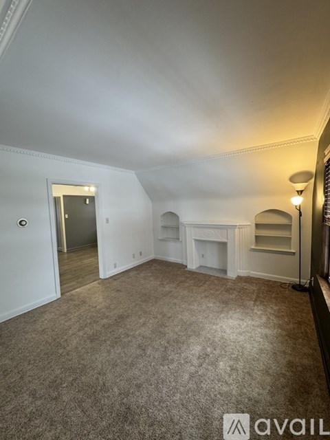 A room with a carpeted floor and a fireplace.