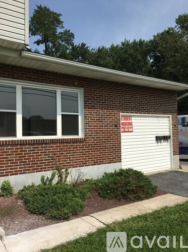 A brick building with a white garage door and a sign that says "Student Housing".
