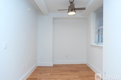 A room with a ceiling fan and wooden flooring.