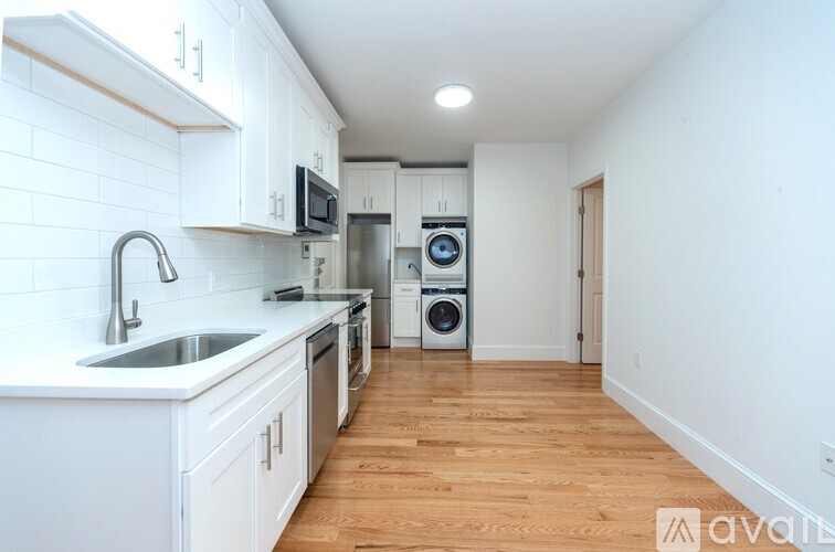 A kitchen with white cabinets and a wooden floor.