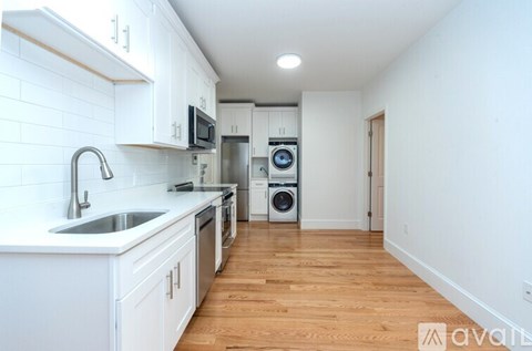A kitchen with white cabinets and a wooden floor.