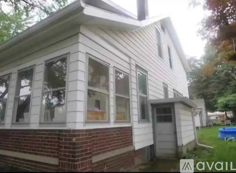 A house with a brick base and a white siding.