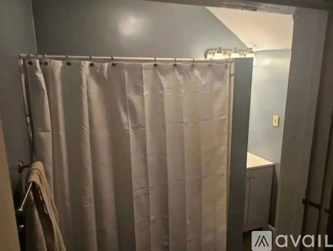A bathroom with a shower curtain and a towel hanging on the rack.