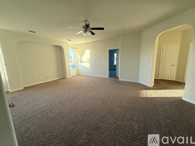 A spacious room with a ceiling fan and carpeted floor.
