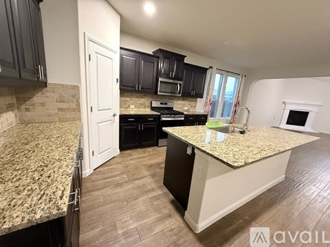 A kitchen with granite countertops and dark cabinets.