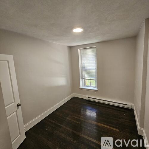 A room with wooden floors and a window with blinds.