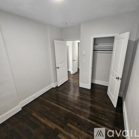 A room with white walls and wooden floors with two open doors.