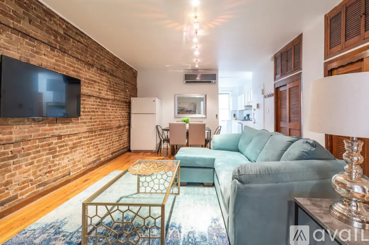 A living room with a brick wall and a television mounted on it.