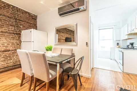 A dining area with a glass table and chairs in front of a brick wall.