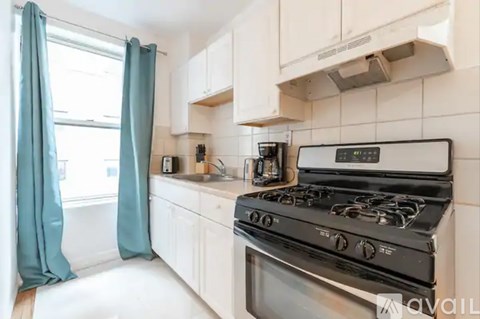 A modern kitchen with a black stove top oven and white cabinets.