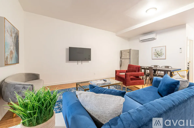 A living room with a blue couch and a television on the wall.