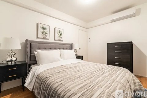 A bedroom with a bed, nightstand, and two framed pictures on the wall.