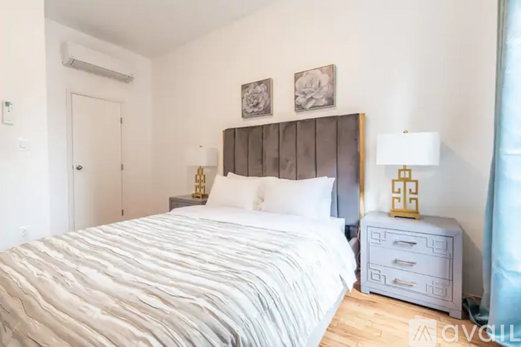 A bedroom with a large bed, a nightstand, and two framed pictures on the wall.