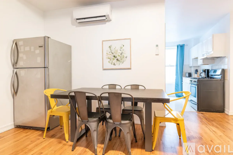 A kitchen with a table and chairs in the foreground and a fridge to the left.