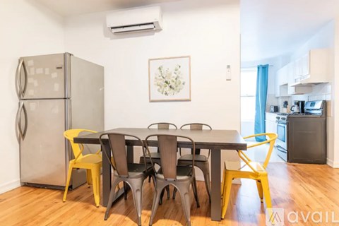 A kitchen with a table and chairs in the foreground and a fridge to the left.