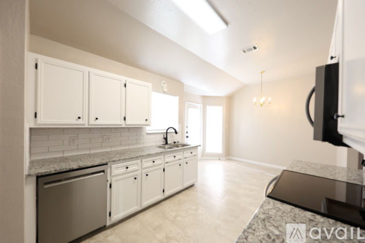 A kitchen with white cabinets and a black fridge.