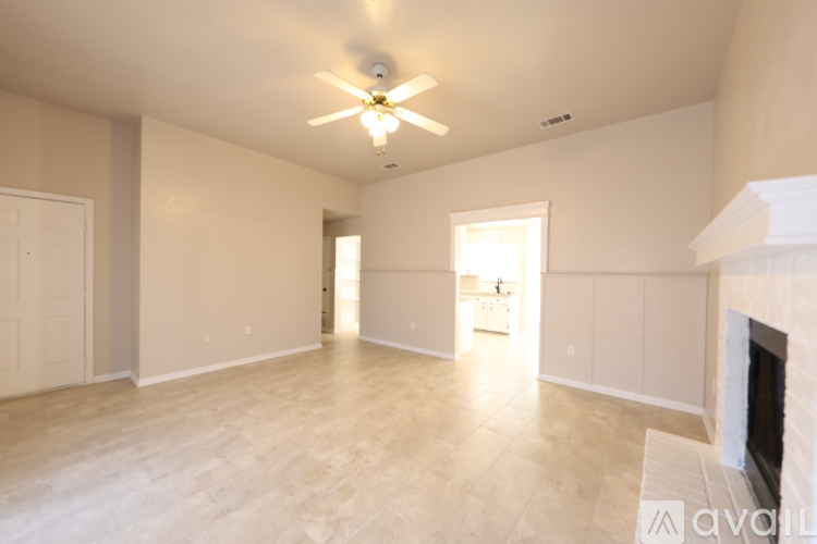 A spacious living room with a fireplace and a ceiling fan.