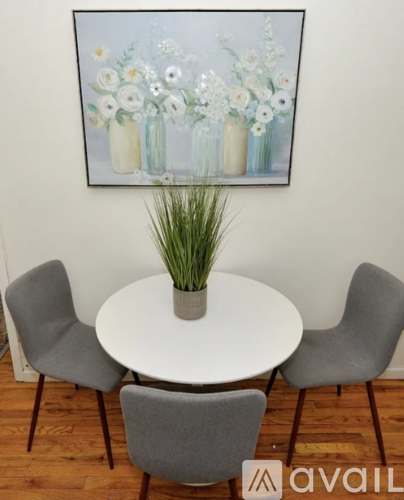 A painting of flowers is hanging on the wall above a table with chairs.