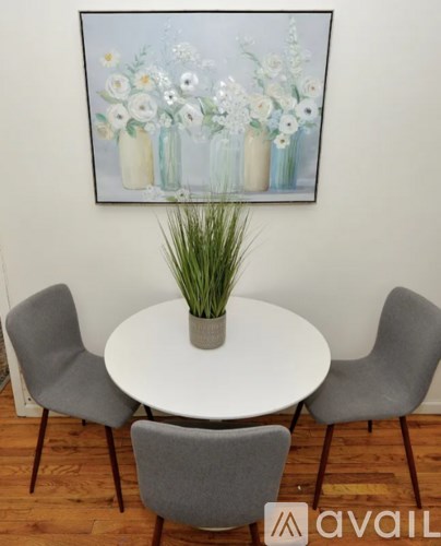 A painting of flowers is hanging on the wall above a table with chairs.