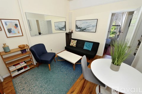 A living room with a blue chair, a white table, and a mirror on the wall.