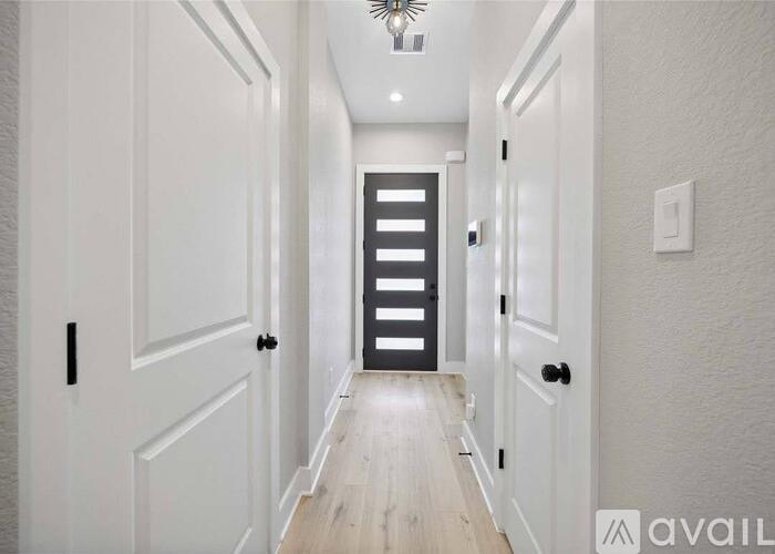 A long hallway with white doors and a light on the ceiling.