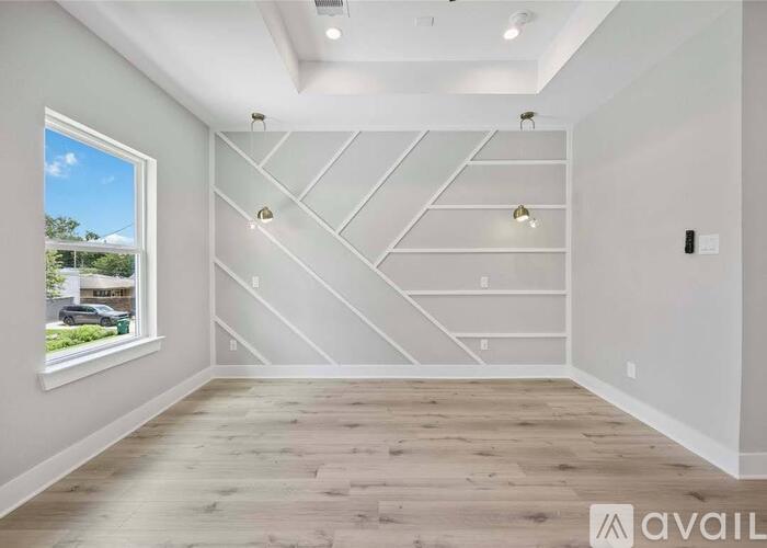 A room with wooden floors and a window showing a blue sky and greenery outside.