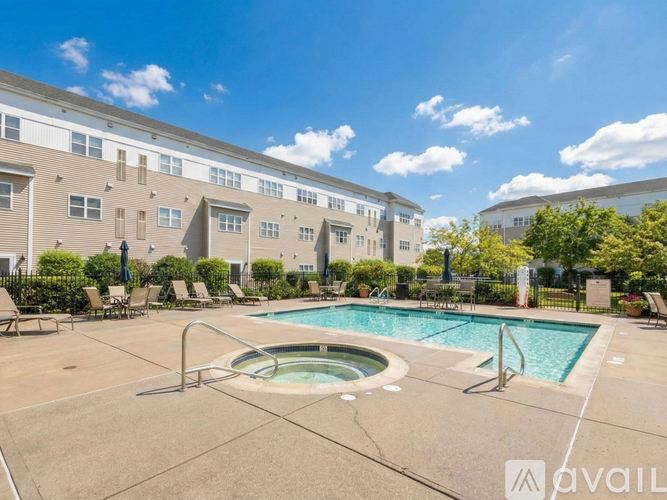 A swimming pool is surrounded by lounge chairs in front of a building.