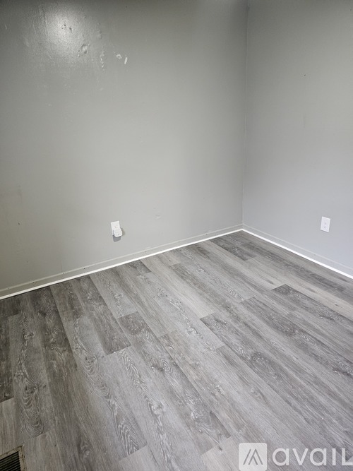 A room with a wooden floor and two switches on the wall.