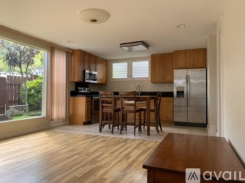 A kitchen with wooden floors and a dining table with chairs.