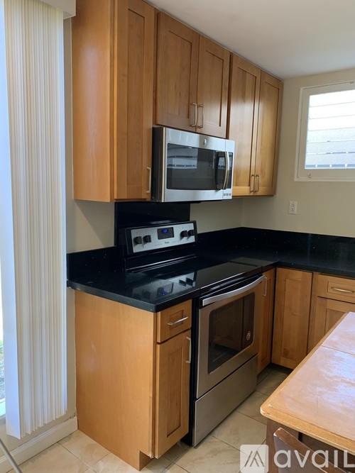 A kitchen with wooden cabinets and black countertops.