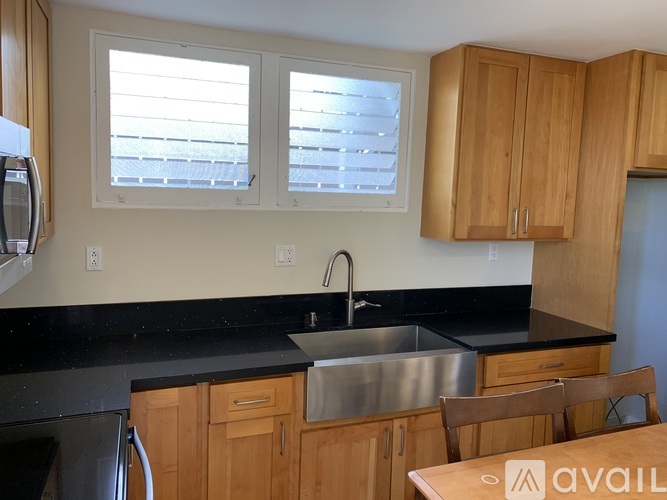 A kitchen with wooden cabinets and black countertops.