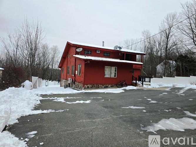 A red house with snow on the ground and trees in the background.