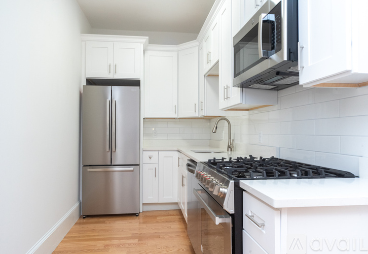 A kitchen with white cabinets and a stainless steel refrigerator.