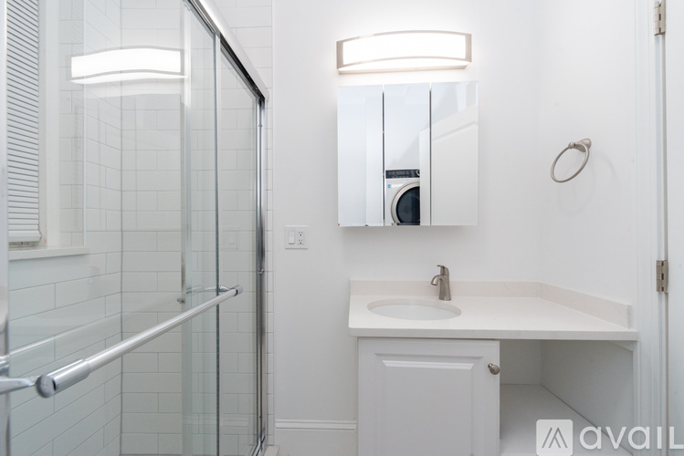 A white bathroom with a sink, mirror, and shower.