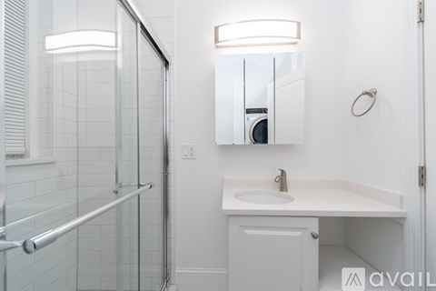 A white bathroom with a sink, mirror, and shower.