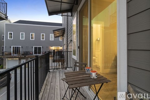 A balcony with a table and chairs is shown with a building in the background.